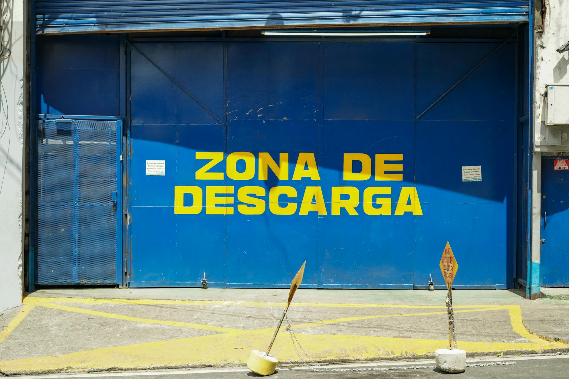 Bright image of a blue loading zone with yellow text 'Zona de Descarga'.