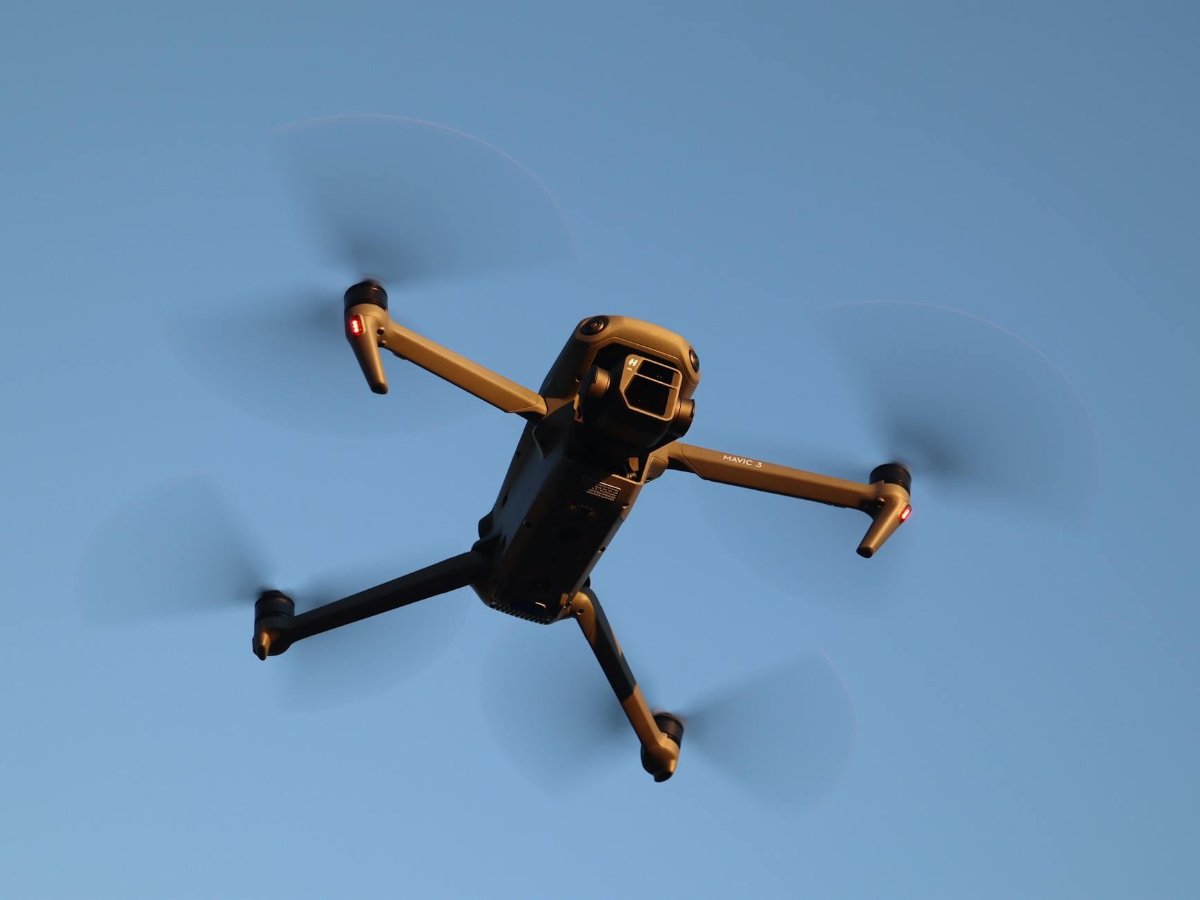 Close-up of a drone flying in a clear blue sky, highlighting its technology and mobility.