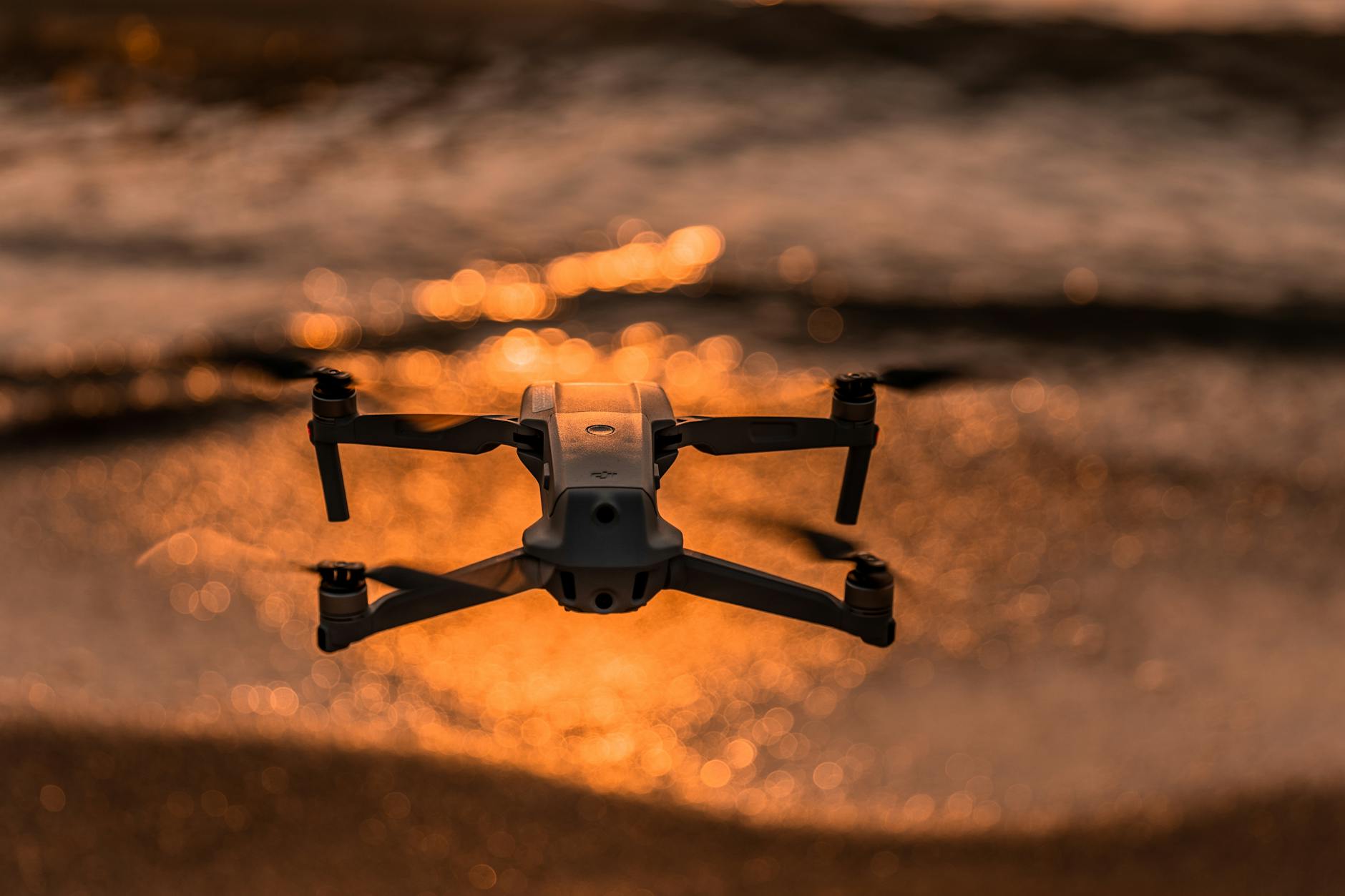 Captivating drone shot flying over shimmering waves illuminated by the golden sunset.
