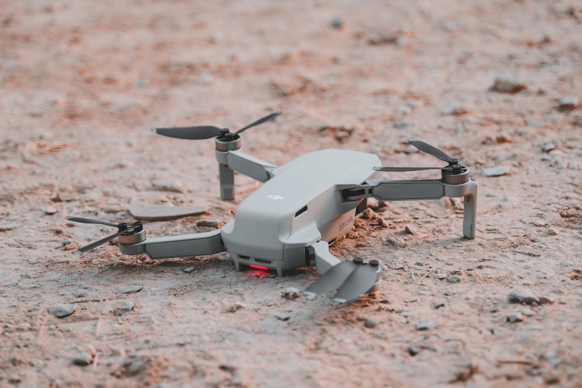 Close-up of a modern drone resting on sandy terrain, highlighting technology and exploration.