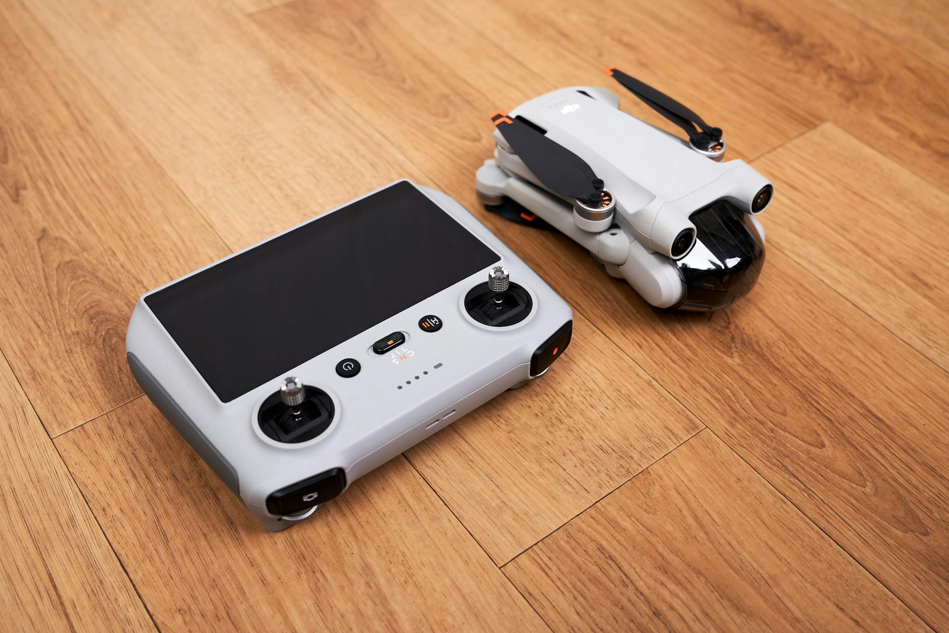 A modern compact drone with its controller set on a wooden surface, ready for flight.