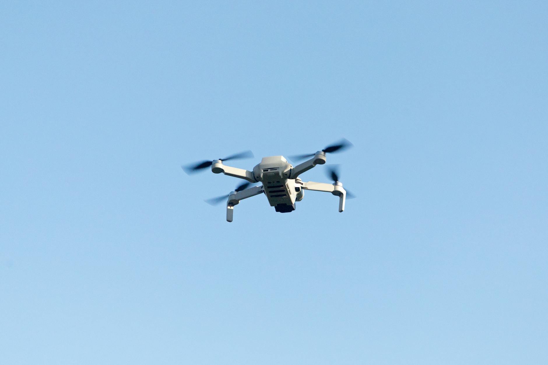 A sleek drone flying high against the clear blue sky, capturing stunning aerial footage.