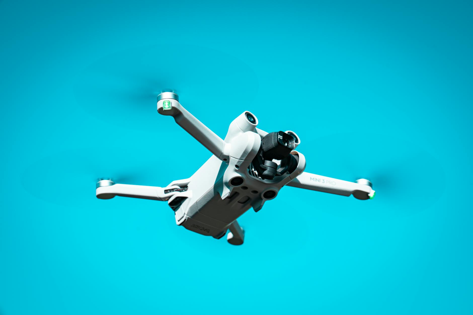 A modern drone flying against a vibrant blue sky, showcasing advanced technology in motion.