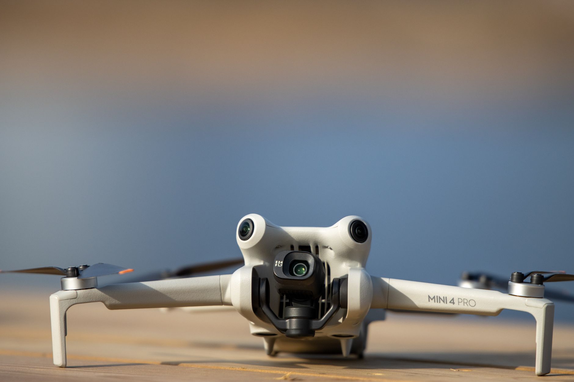 Detailed close-up of a Mini 4 Pro drone on a wooden surface with a blurred background.