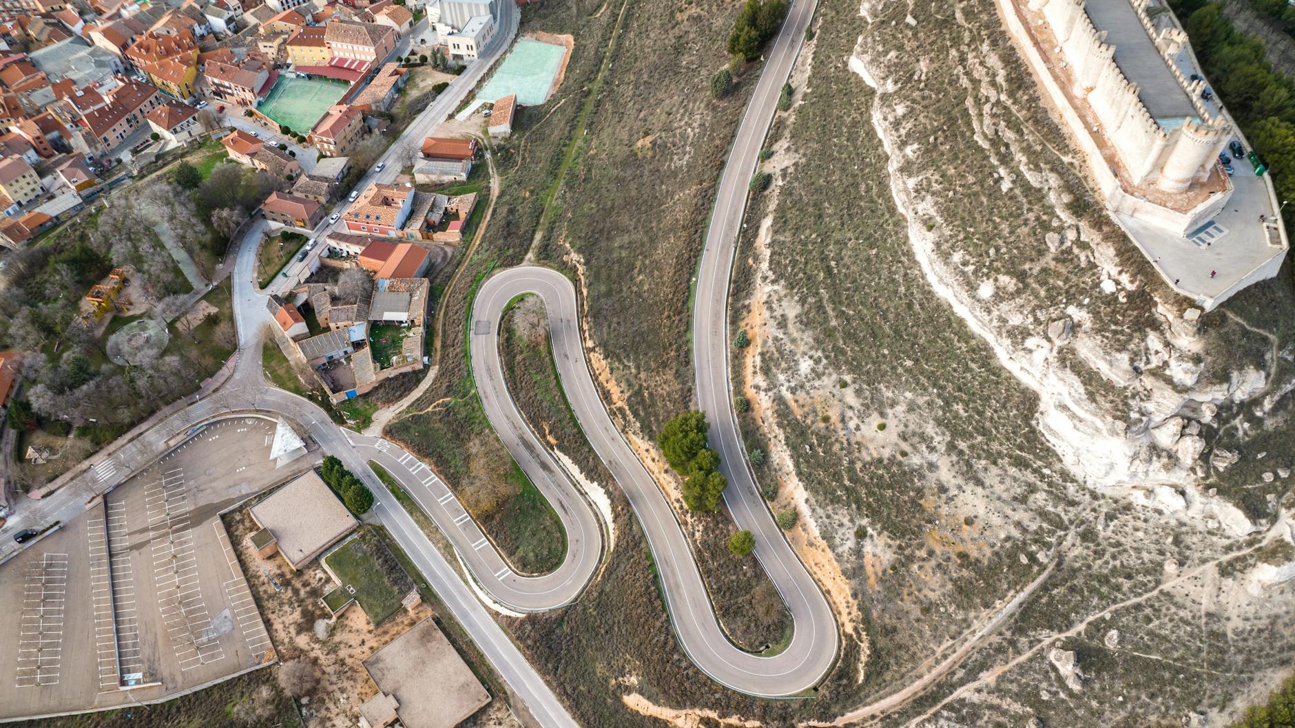 Stunning aerial view of Peñafiel Castle and winding road, showcasing the unique landscape of Valladolid, Spain.