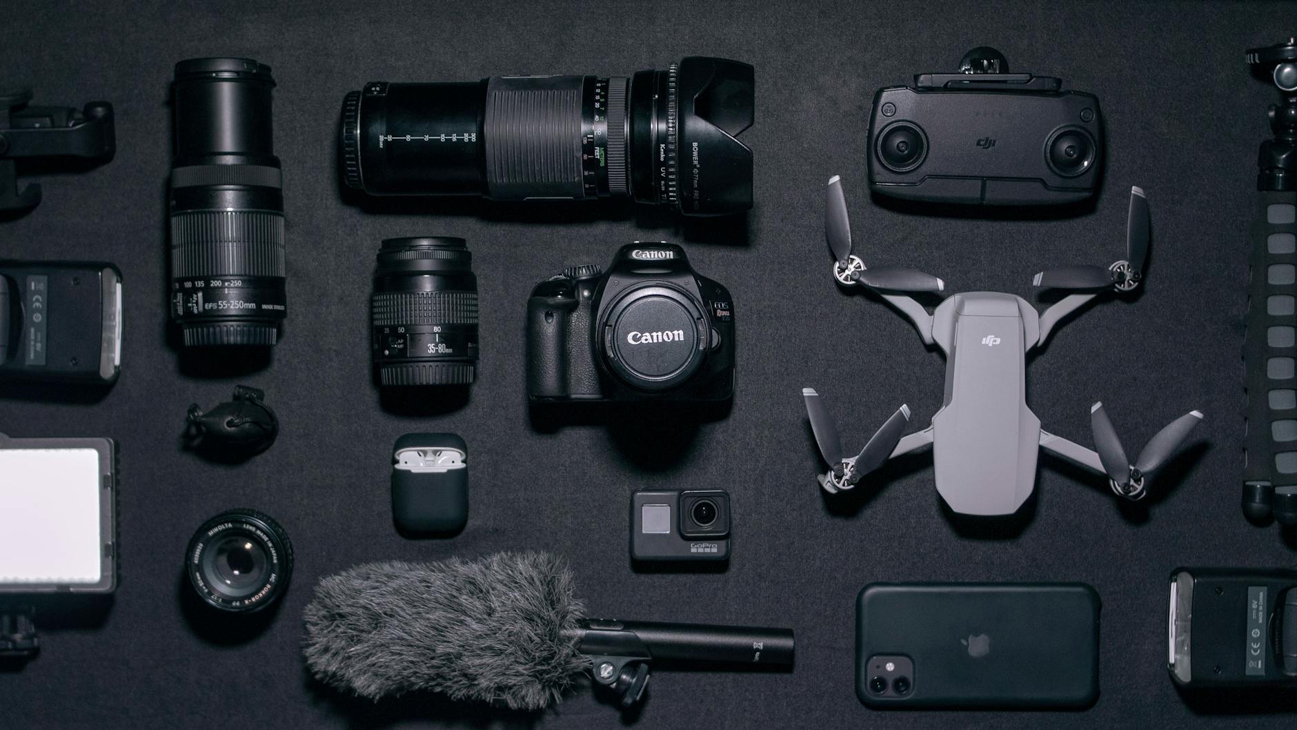 Top view of various photography gadgets and drone displayed on a dark surface.