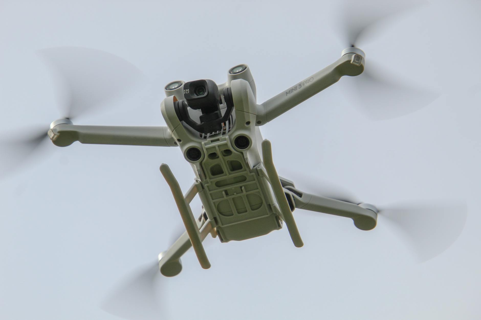 Aerial drone flying against a clear sky, showcasing its sleek design and propellers in motion.